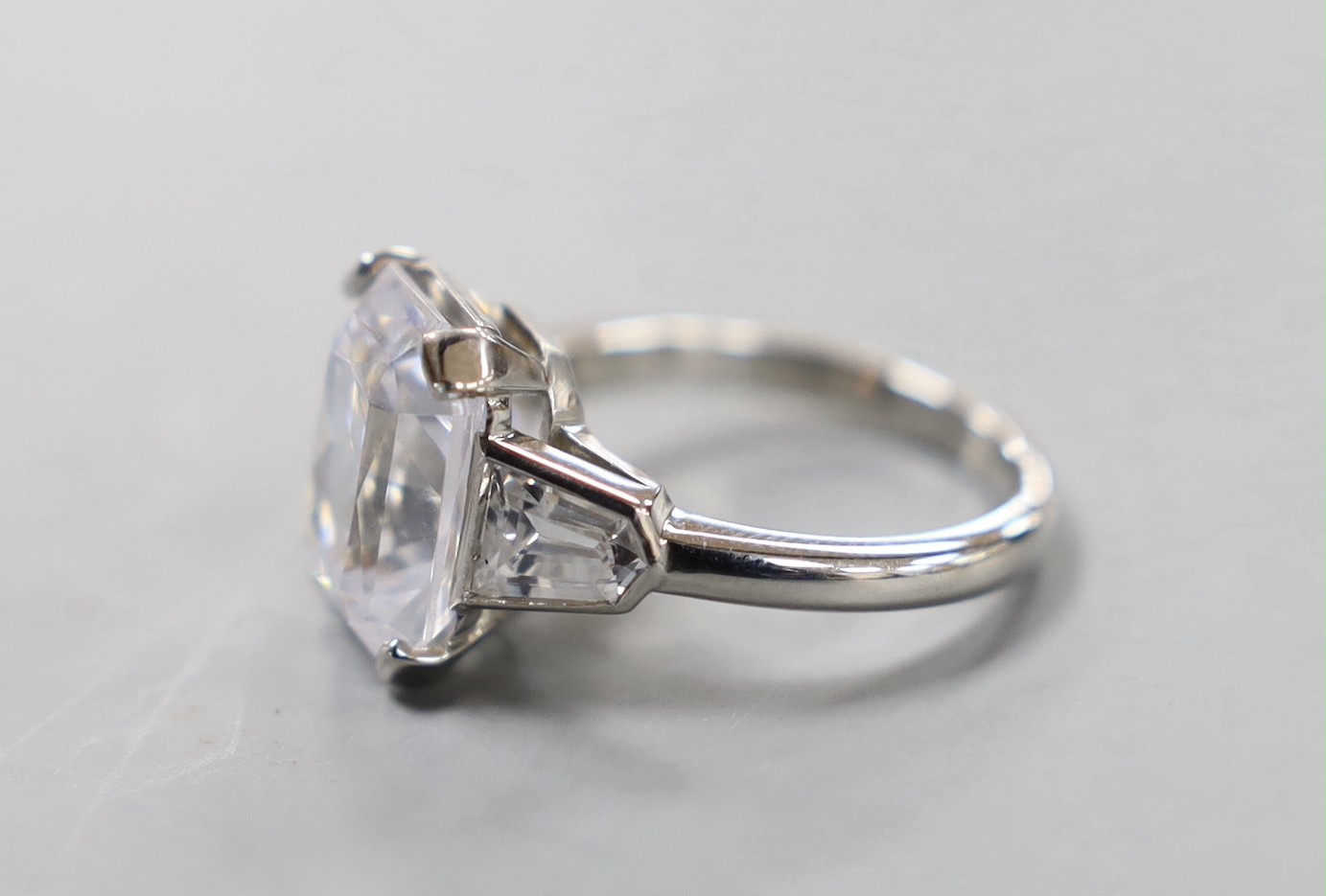 A white metal (stamped Plat) and fancy cut singe stone cubic zirconia set dress ring, with cubic zirconia set shoulders, size O, gross weight 9.7 grams.